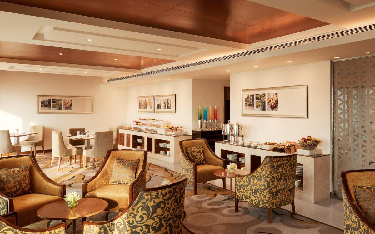 a restaurant with chairs and tables and a bar at Taj Swarna, Amritsar in Amritsar