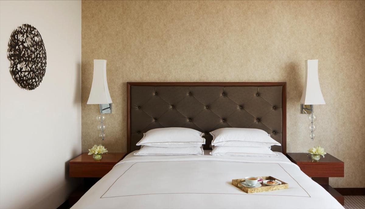 a bedroom with a large bed with white sheets and pillows at Taj Swarna, Amritsar in Amritsar