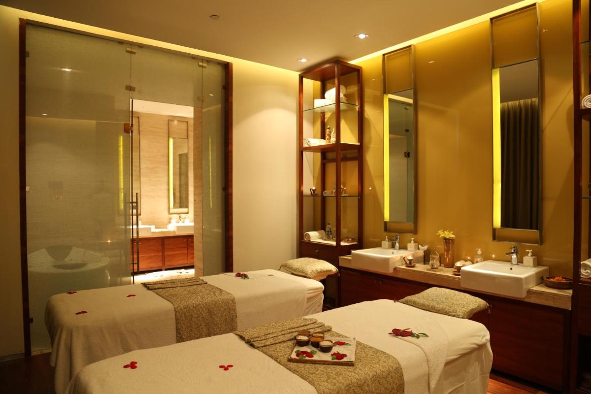 a bathroom with two beds and a sink and a mirror at Taj City Centre Gurugram in Gurgaon