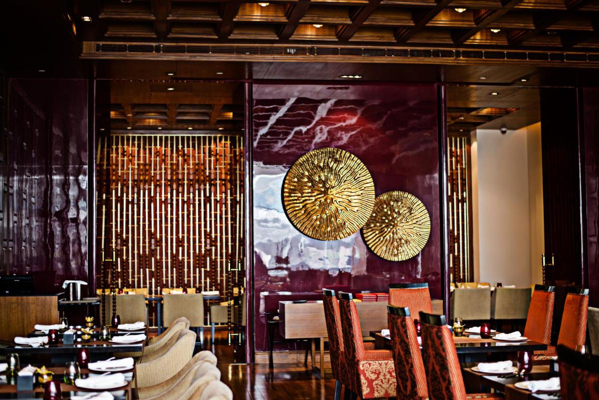 a dining room with tables and chairs and chandeliers at Taj City Centre Gurugram in Gurgaon