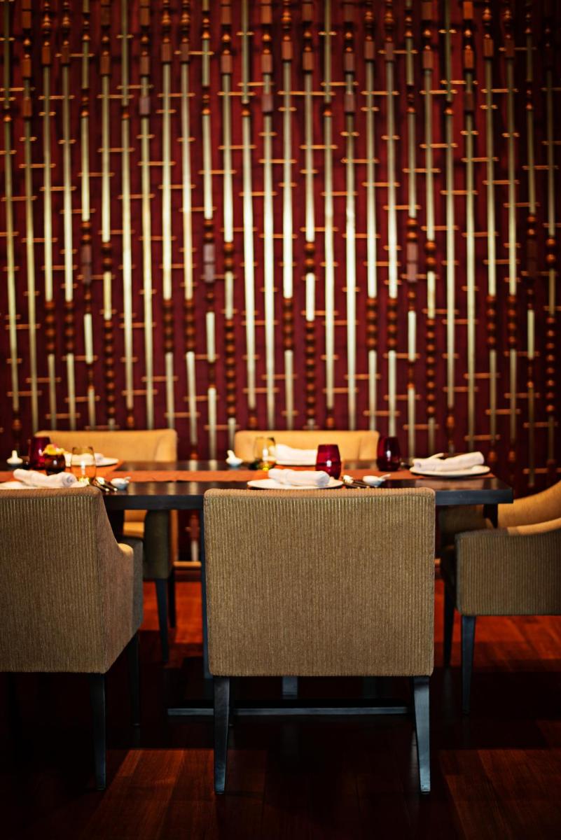 a dining room with a table and chairs and a wall at Taj City Centre Gurugram in Gurgaon