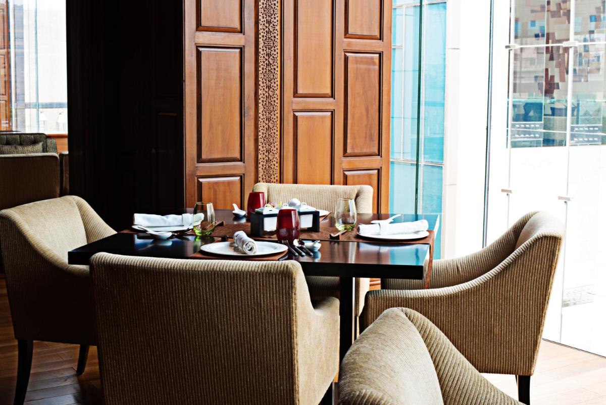 a dining room with a table and chairs and a window at Taj City Centre Gurugram in Gurgaon