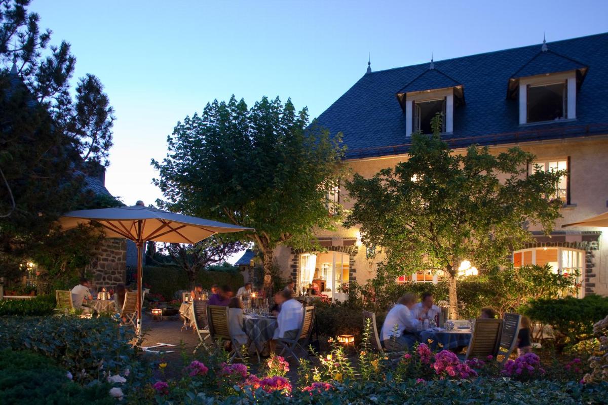 un groupe de personnes assises à des tables devant un bâtiment dans l'établissement Le Bailliage Hôtel & Spa, à Salers