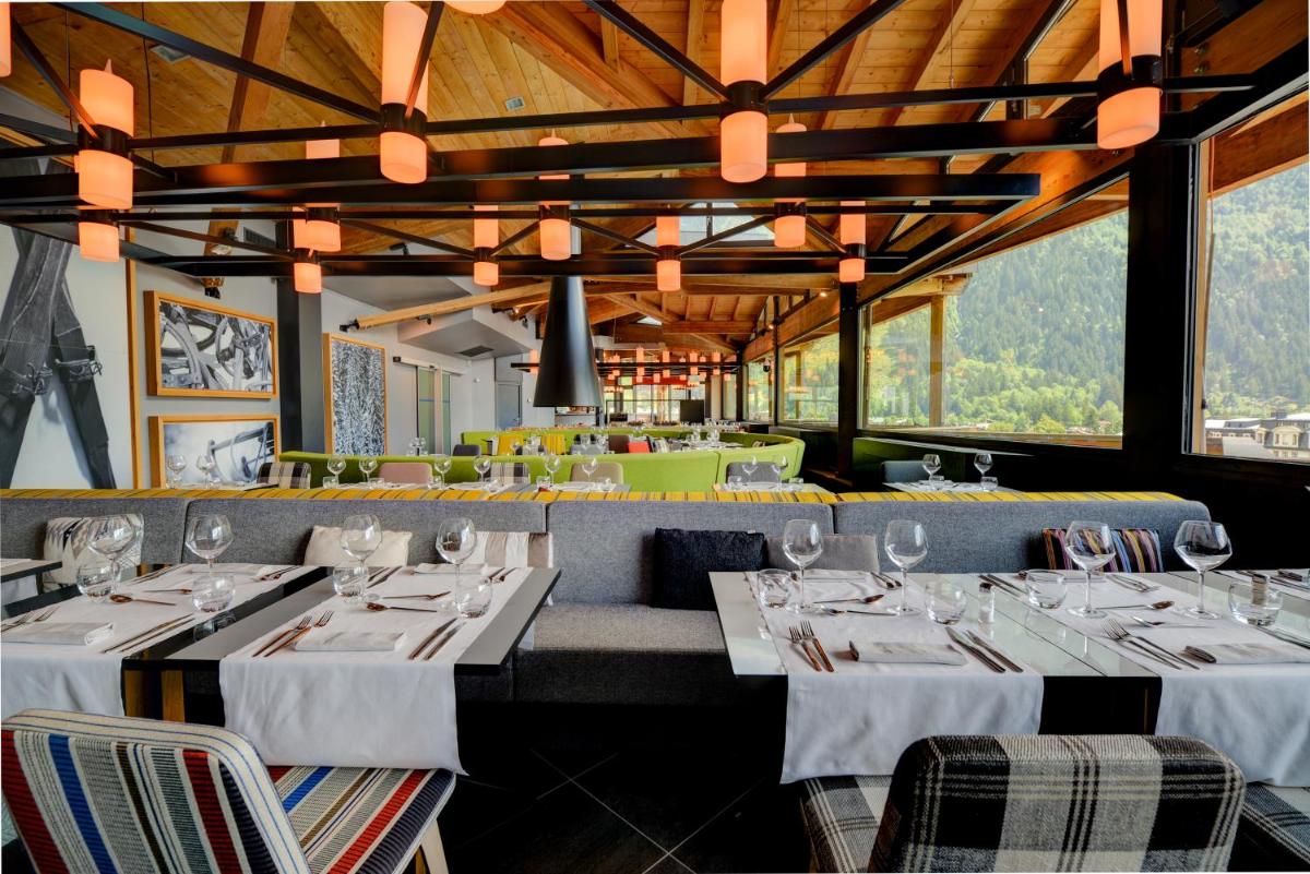 un restaurant avec des tables et des chaises blanches et des fenêtres dans l'établissement Alpina Eclectic Hotel, à Chamonix-Mont-Blanc