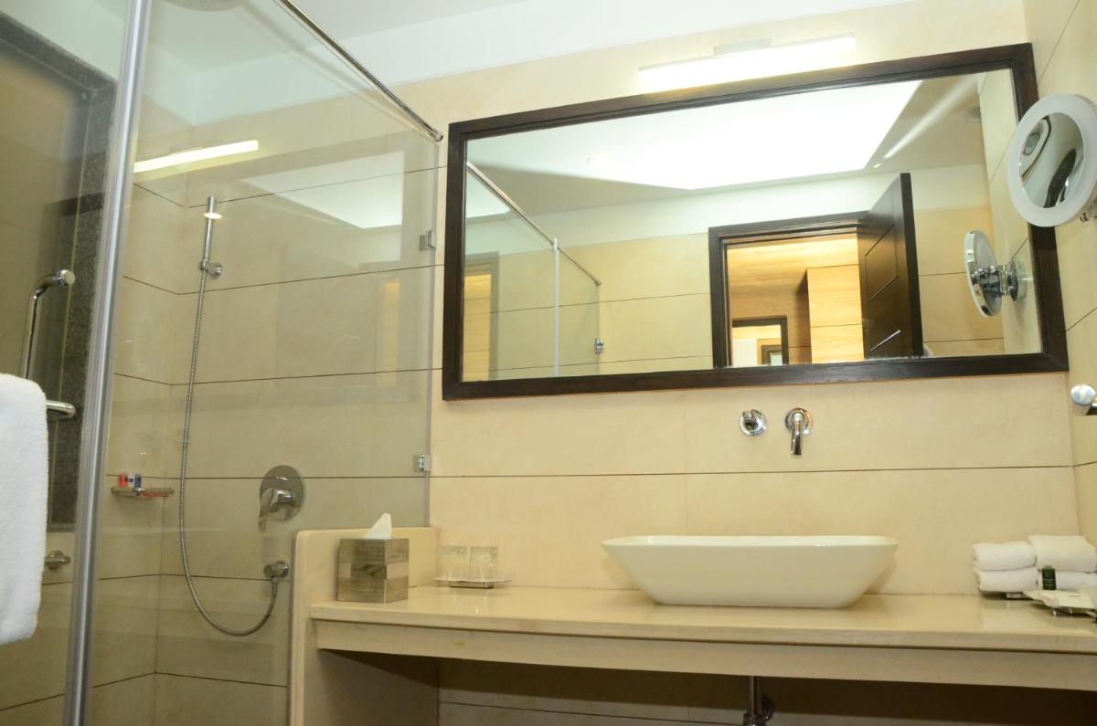 a bathroom with a sink and a shower with a mirror at Radisson Chandigarh Zirakpur in Chandīgarh