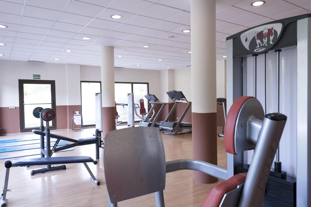 un gimnasio con filas de cintas de correr y máquinas de cardio en Hotel Real Balneario Carlos III, en Trillo