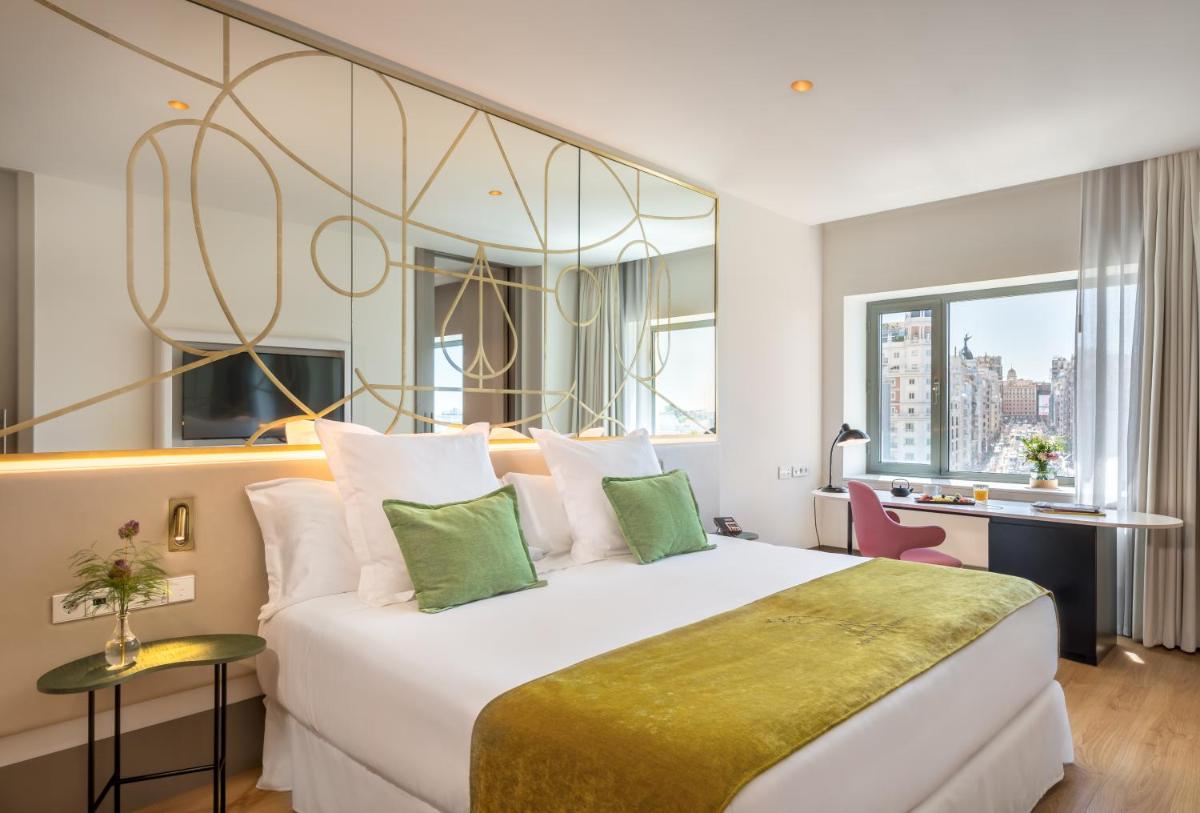 Una habitación de hotel con una cama grande y un escritorio. en Barceló Torre de Madrid, en Madrid