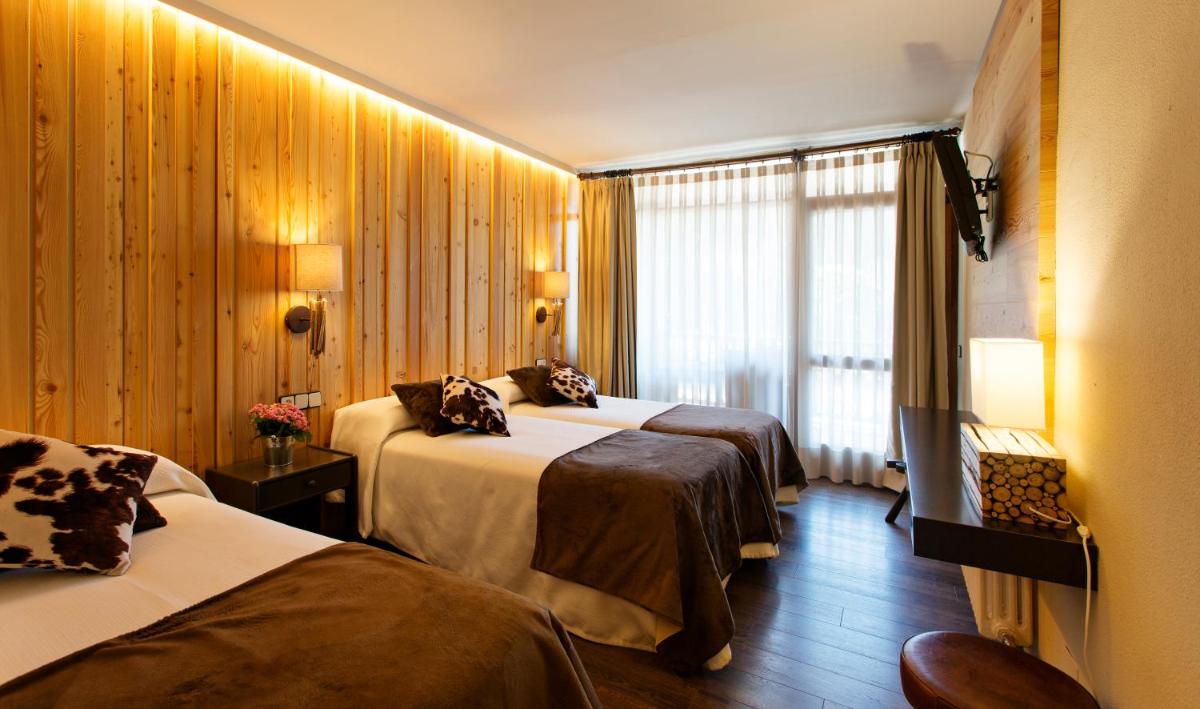 Una habitación de hotel con dos camas y una ventana. en Hotel La Coma, en Setcases