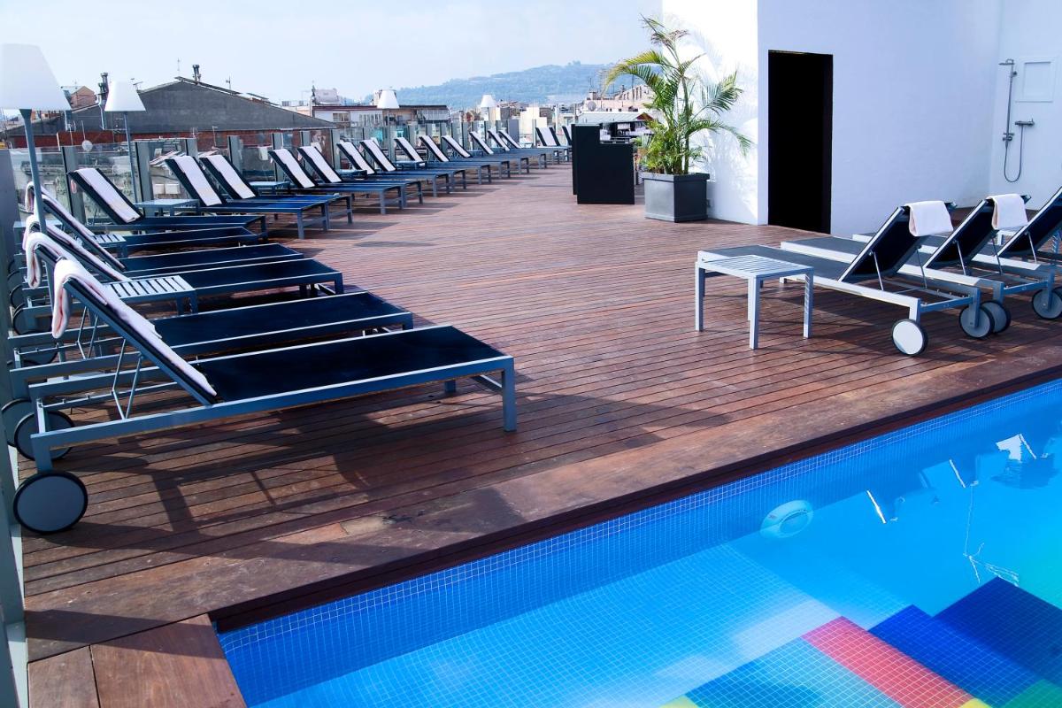 Una fila de tumbonas junto a una piscina. en Axel Hotel Barcelona - Adults Only, en Barcelona