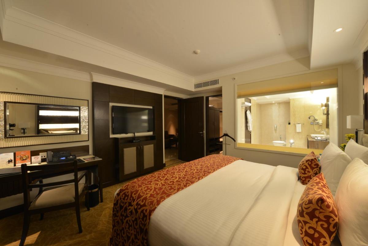 a bedroom with a bed and a desk and a television at Ramada Plaza Chennai in Chennai