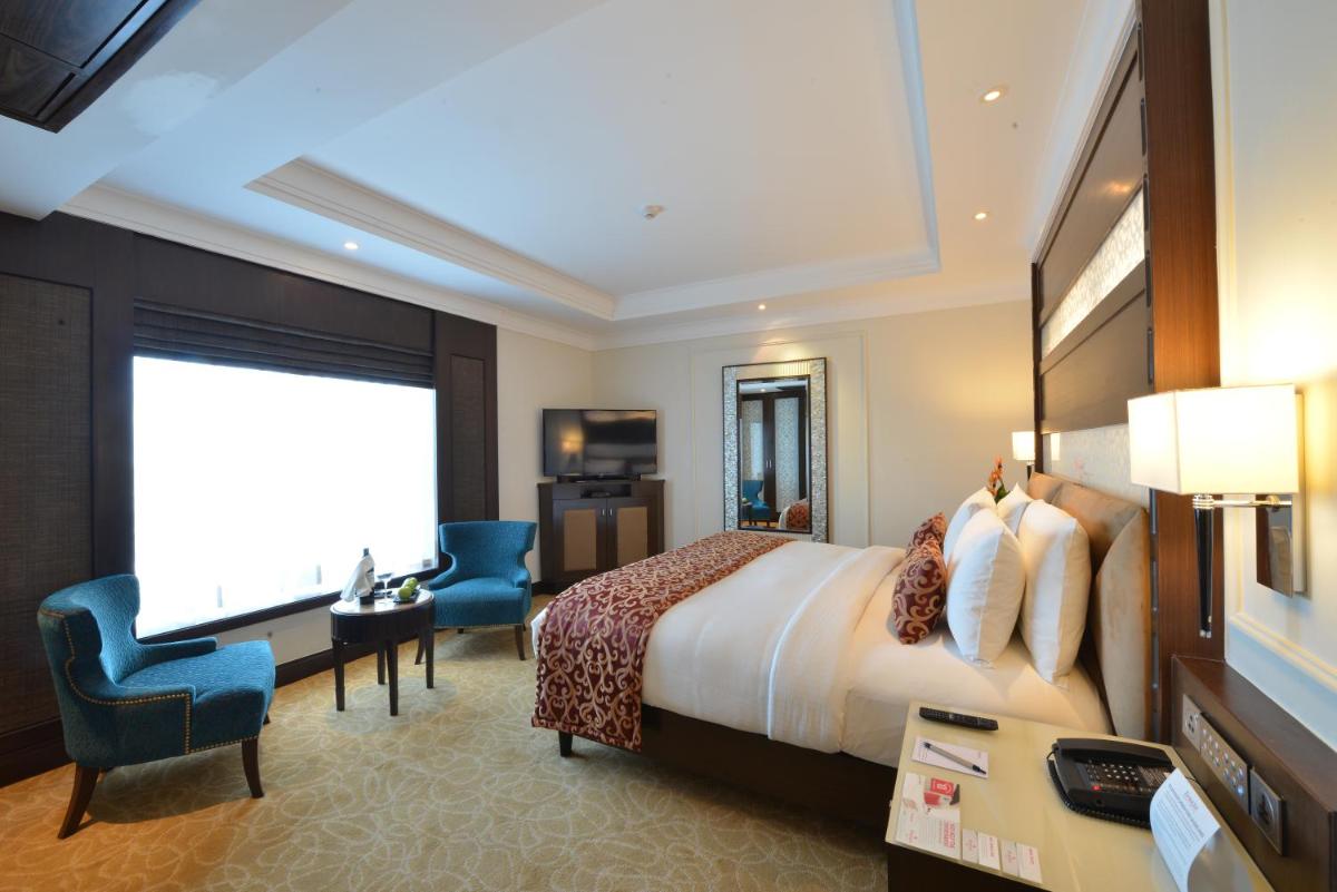 a hotel room with a bed and a desk and chair at Ramada Plaza Chennai in Chennai