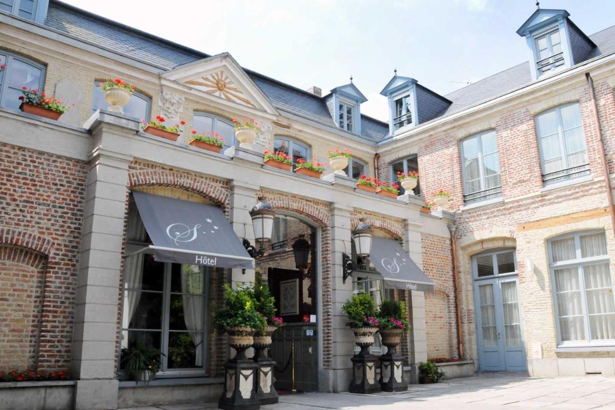 un bâtiment en briques avec des plantes en pot devant un magasin dans l'établissement Châtellerie De Schoebeque, à Cassel