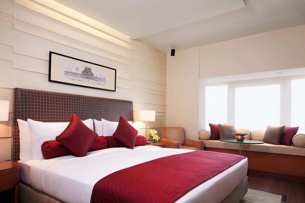 a bedroom with a large bed with red pillows at Taj Coromandel in Chennai