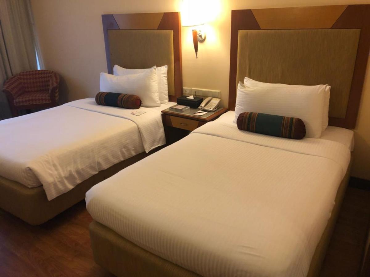 a hotel room with two beds and a night stand at The Lalit Ashok in Bengaluru a hotel room with two beds and a night stand at The Lalit Ashok in Bengaluru
