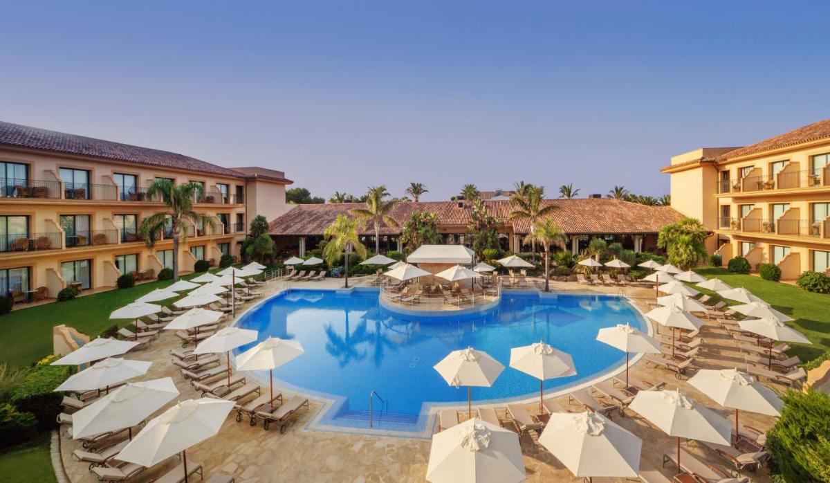 Una vista aérea de una piscina del complejo con sillas y sombrillas. en La Quinta Menorca by PortBlue Boutique - Adults Only, en Cala'n Bosch
