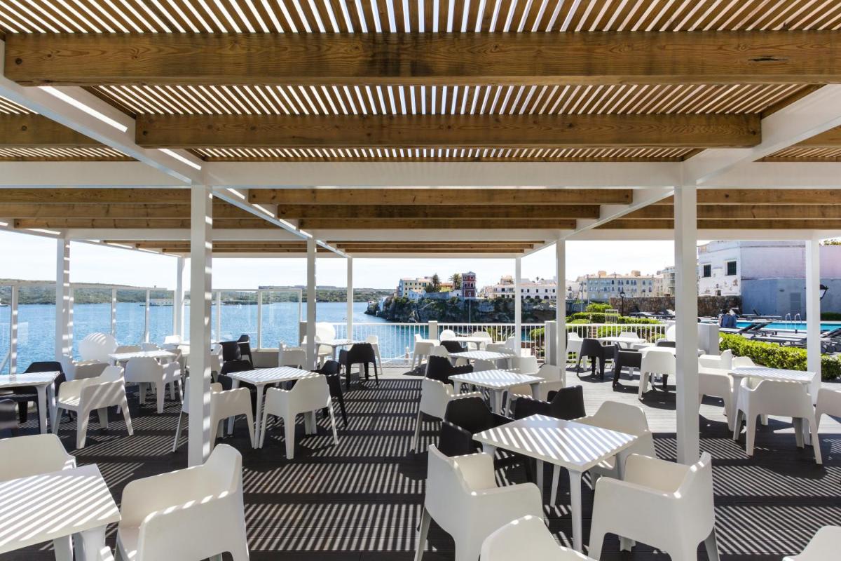 un restaurante con mesas blancas y sillas en una terraza en ARTIEM Carlos - Adults Only, en Es Castell