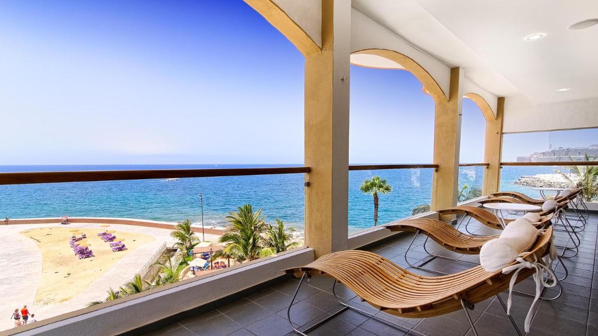 Un balcón con sillas y vista al mar. en Bull Dorado Beach & SPA, en La Playa de Arguineguín