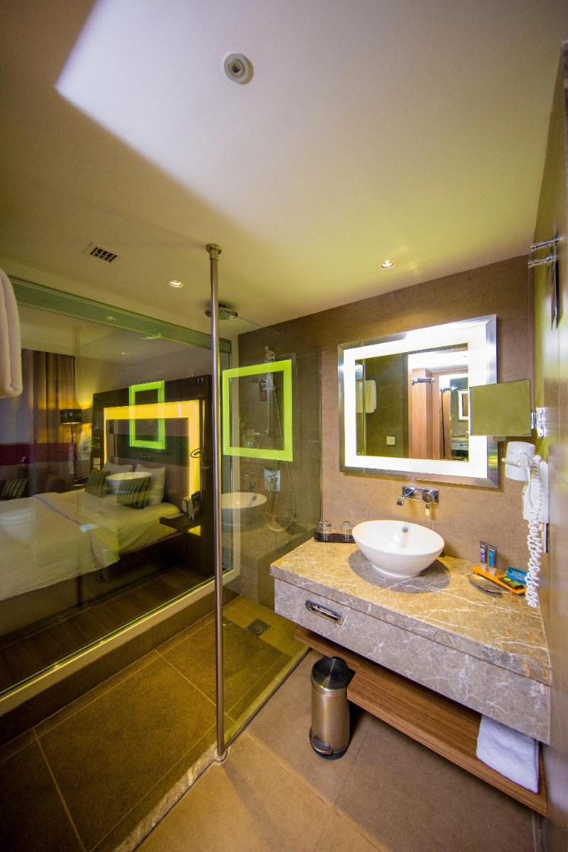 a bathroom with a sink and a shower and a bed at Novotel Chennai Sipcot in Chennai