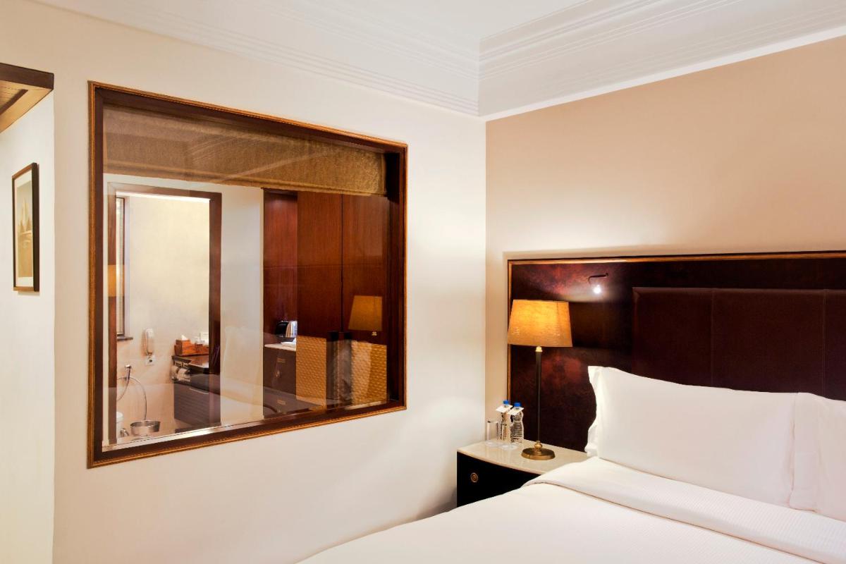 a bedroom with a bed and a large mirror at Eros Hotel New Delhi, Nehru Place in New Delhi a bedroom with a bed and a large mirror at Eros Hotel New Delhi, Nehru Place in New Delhi