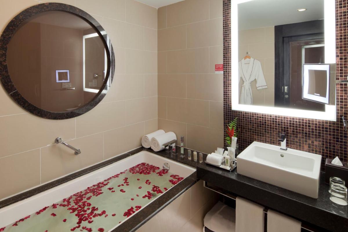 a bathroom with a tub and a sink and a mirror at The Oterra in Bengaluru