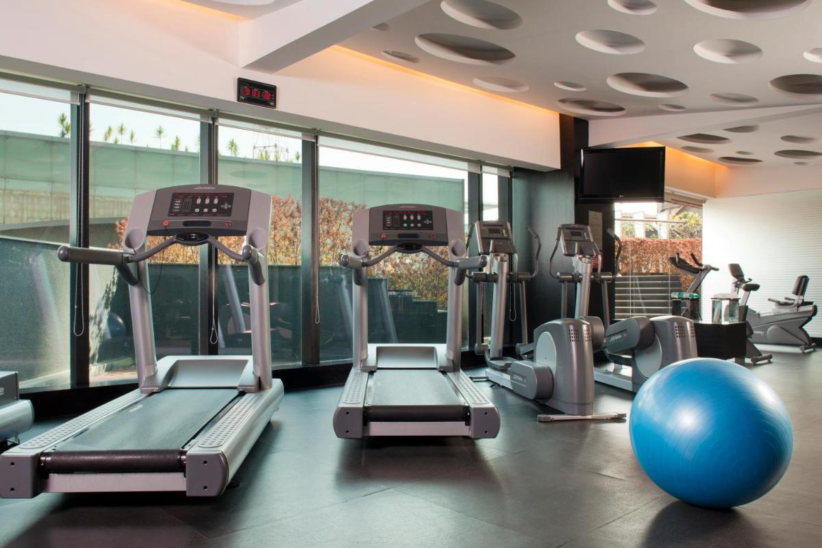a gym with cardio machines and a large window at The Oterra in Bengaluru