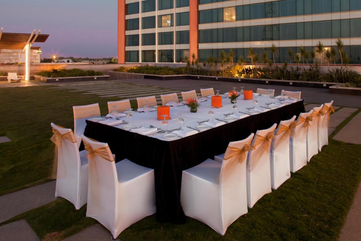 a long table with white tables and chairs in front of a building at The Oterra in Bengaluru