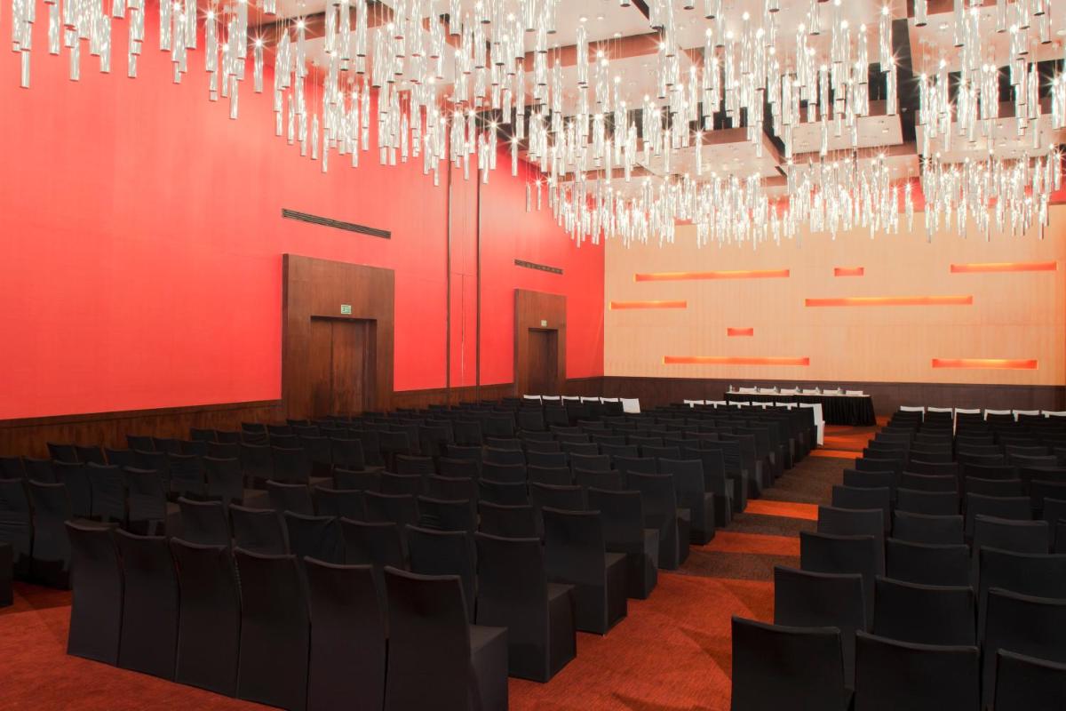 a large room with black chairs and chandeliers at The Oterra in Bengaluru