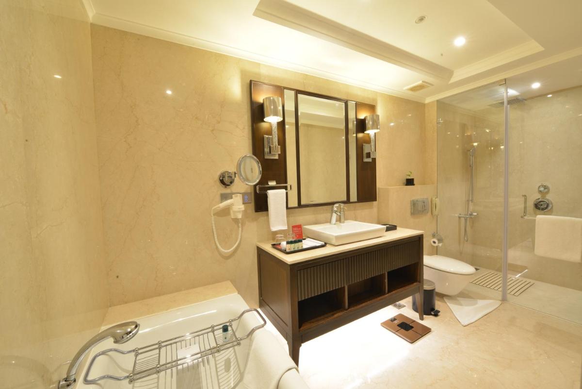 a bathroom with a sink and a toilet and a mirror at Ramada Plaza Chennai in Chennai