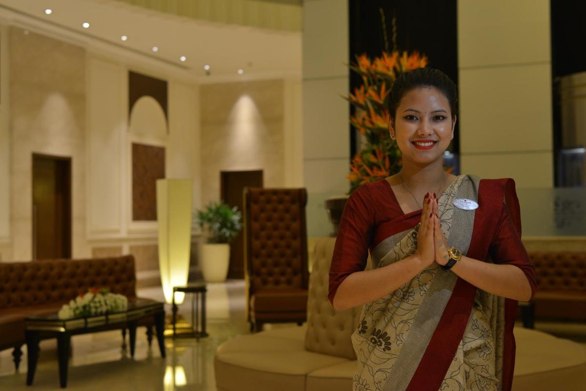 a woman is standing in a lobby with her hands at Ramada Plaza Chennai in Chennai