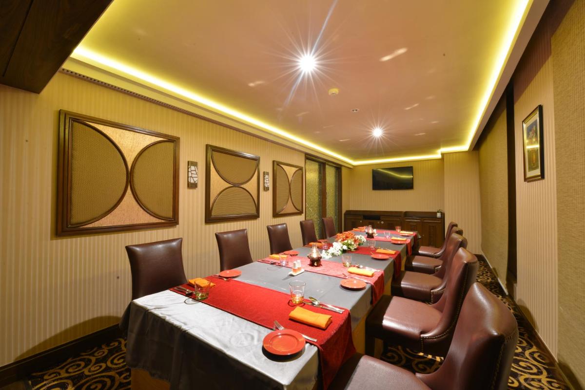 a dining room with a long table and chairs at Ramada Plaza Chennai in Chennai