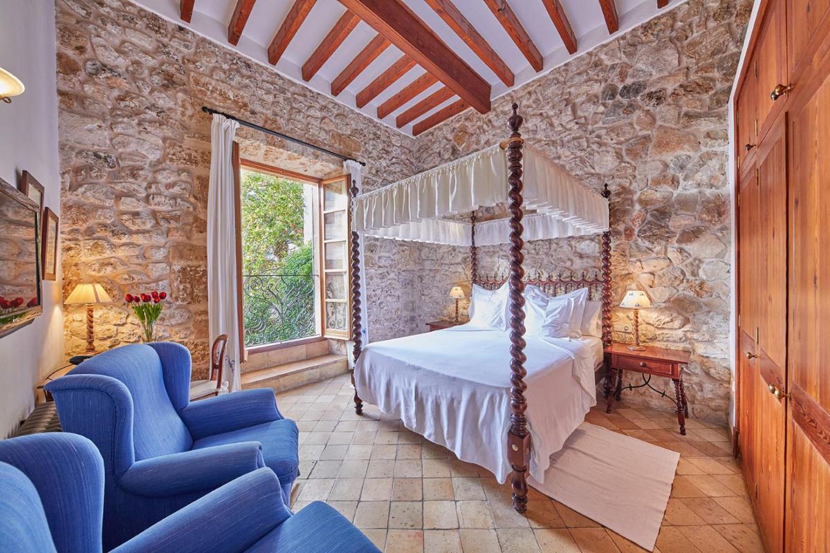 1 dormitorio con 1 cama con dosel y sillas azules en Cas Comte Suites & Spa - Adults Only, en Lloseta