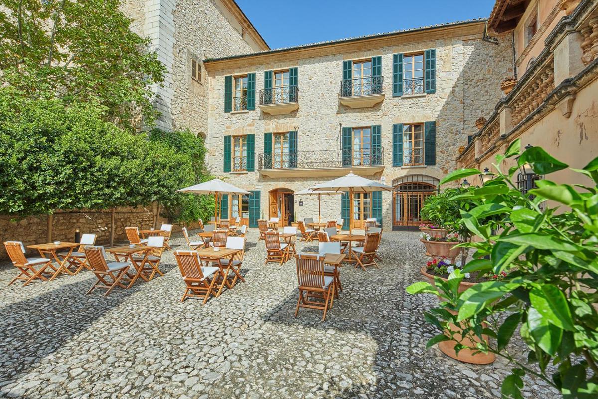 Un patio al aire libre con mesas y sillas y un edificio. en Cas Comte Suites & Spa - Adults Only, en Lloseta