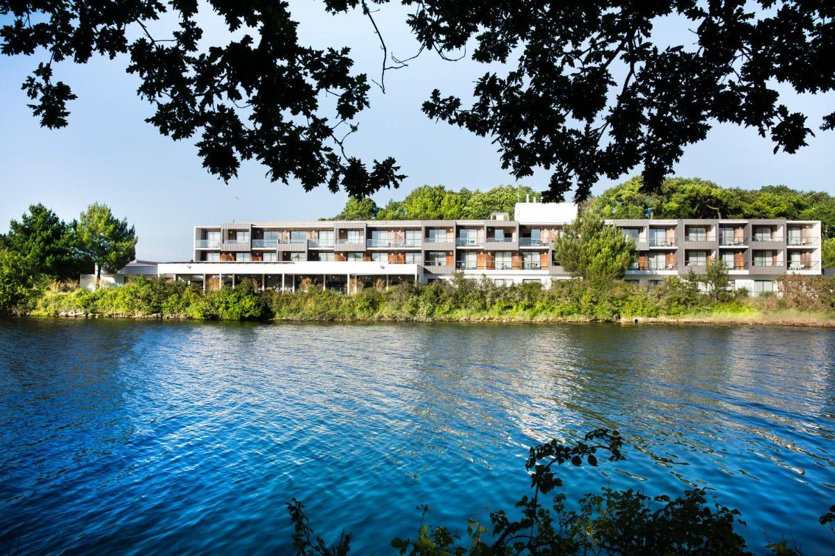 un bâtiment sur le bord d'une rivière dans l'établissement Best Western Plus Hotel les Rives du Ter, à Larmor-Plage