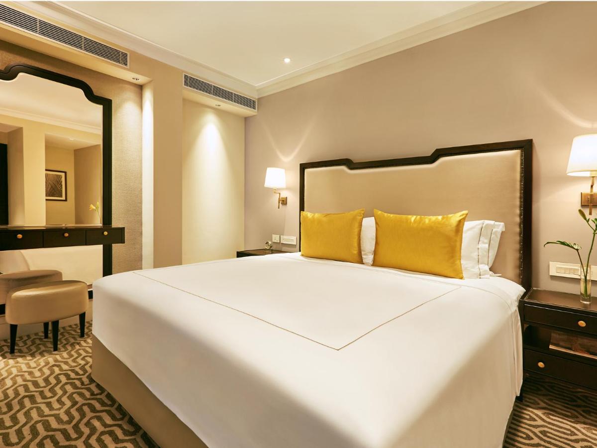 a bedroom with a large white bed with yellow pillows at Taj Connemara, Chennai in Chennai