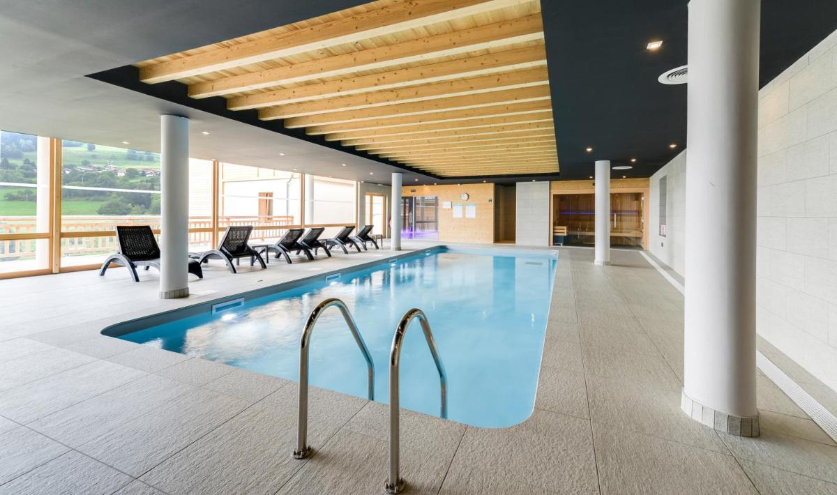 une piscine dans un bâtiment avec des chaises autour dans l'établissement TERRESENS - Les Fermes du Mont-Blanc, à Combloux