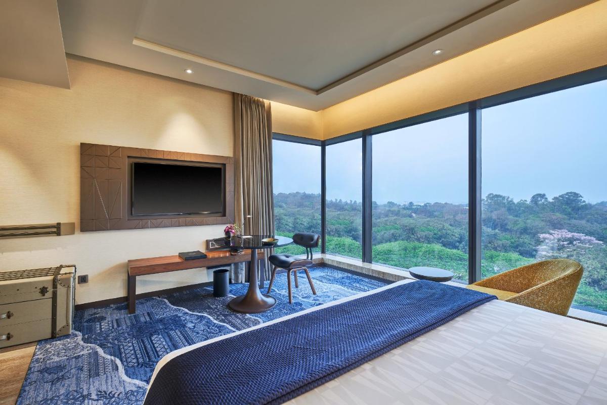 a hotel room with a bed and a tv at The Den, Bengaluru in Bengaluru