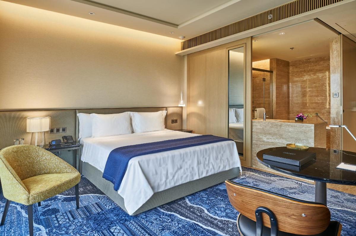 a hotel room with a bed and a bathroom at The Den, Bengaluru in Bengaluru