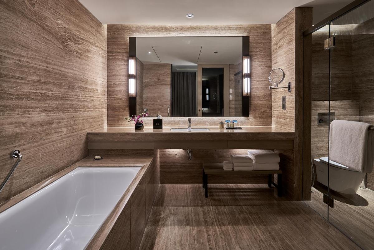 a bathroom with a tub and a sink and a mirror at The Den, Bengaluru in Bengaluru