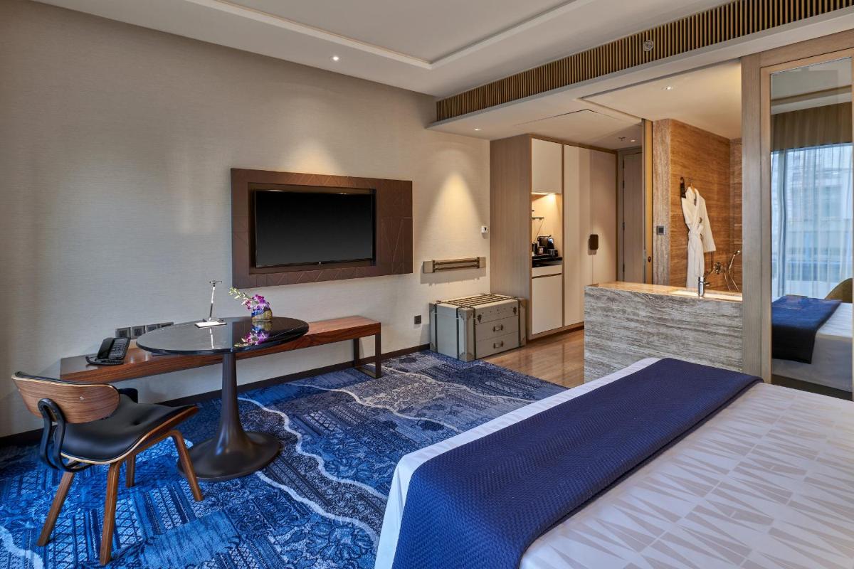 a hotel room with a bed and a desk and a television at The Den, Bengaluru in Bengaluru