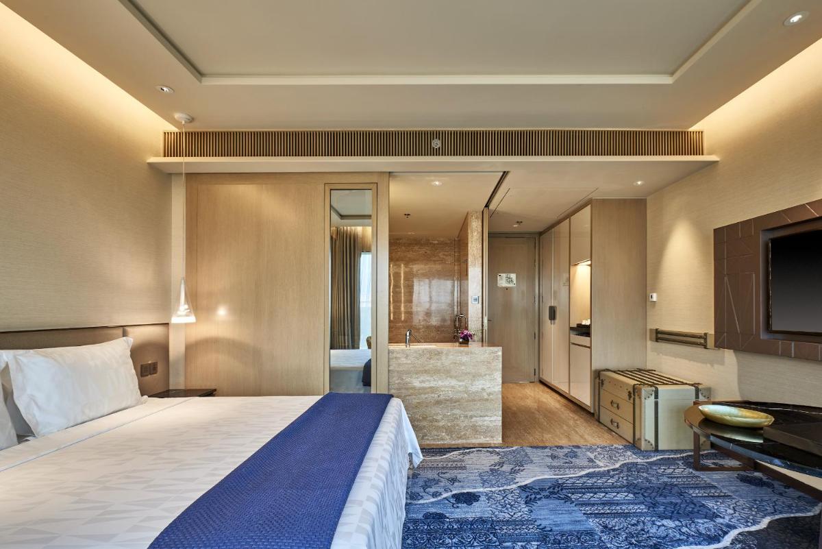 a hotel room with a bed and a bathroom at The Den, Bengaluru in Bengaluru