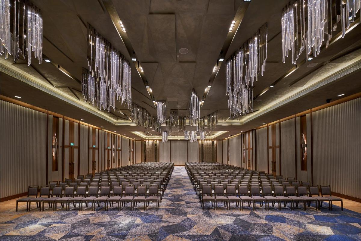 an empty hall with rows of chairs and chandeliers at The Den, Bengaluru in Bengaluru