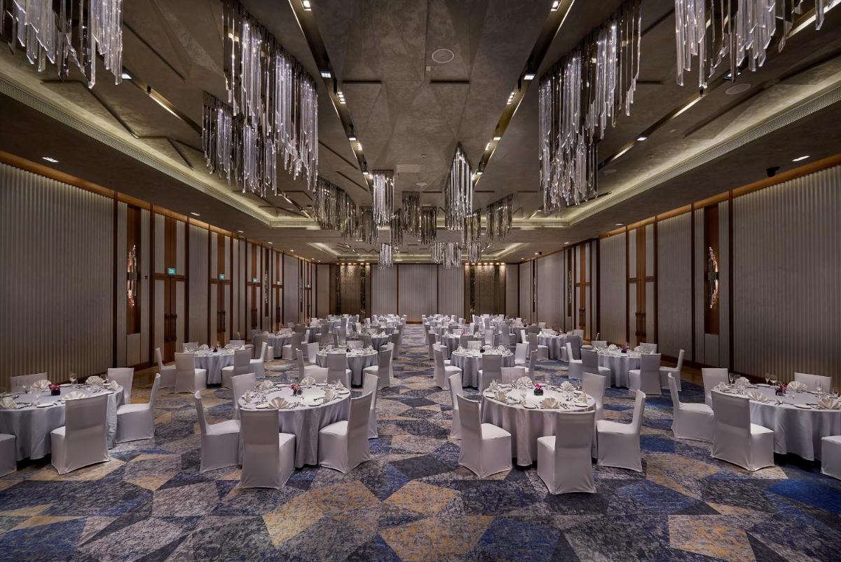 a banquet hall with white tables and chairs and chandeliers at The Den, Bengaluru in Bengaluru