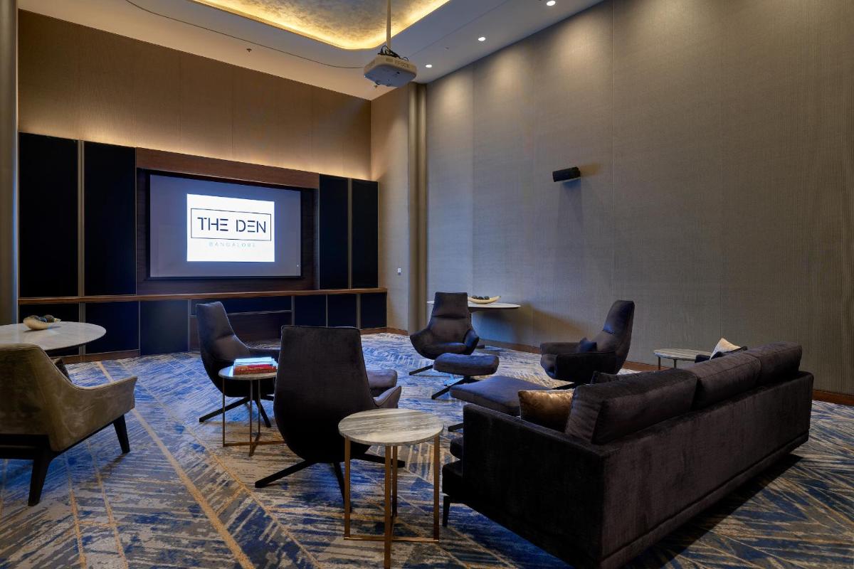 a waiting room with couches and a projection screen at The Den, Bengaluru in Bengaluru