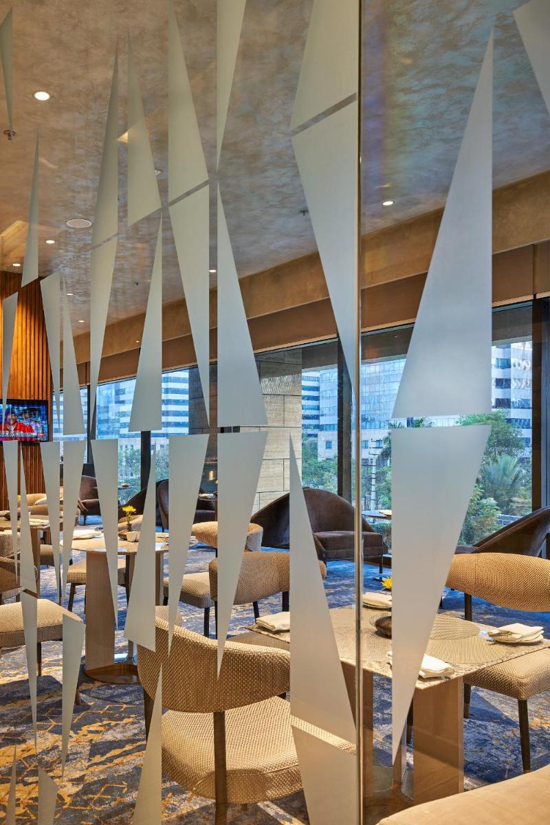 a dining room with tables and chairs and mirrors at The Den, Bengaluru in Bengaluru