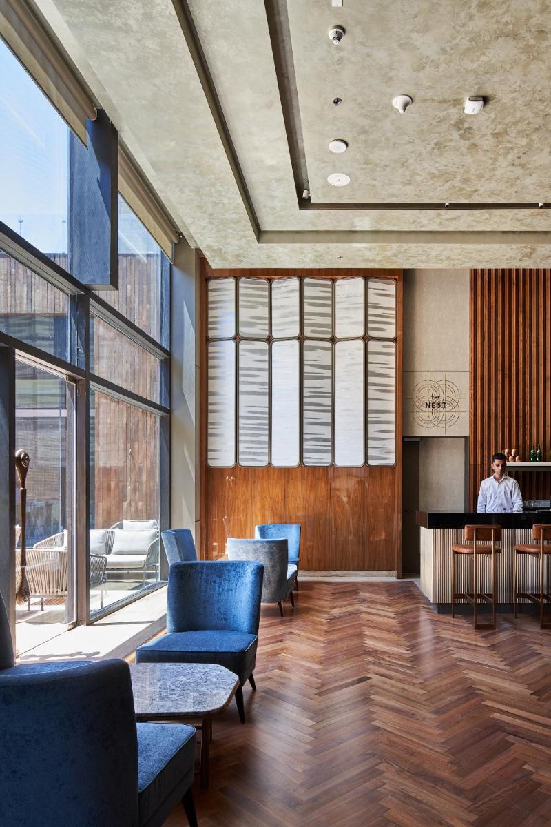 a lobby with blue chairs and a person sitting at a table at The Den, Bengaluru in Bengaluru