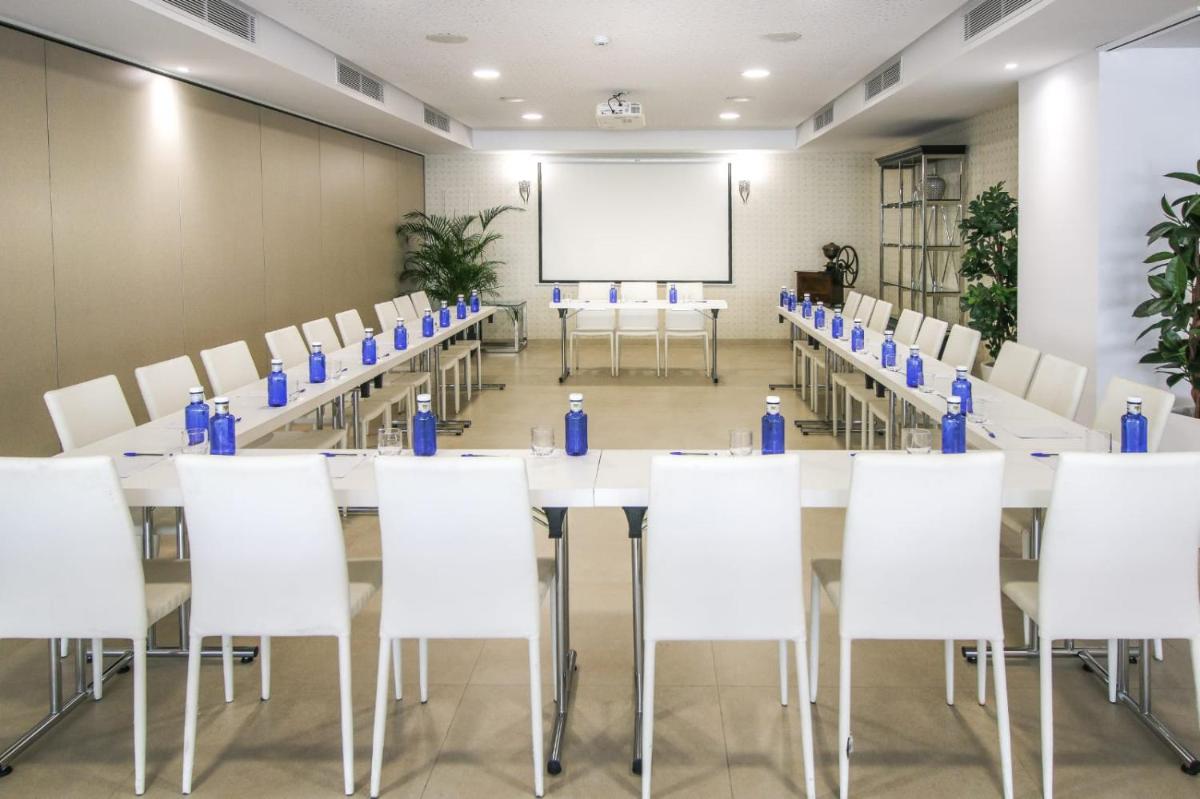 una sala de conferencias con mesas y sillas blancas y una pizarra en Tomir Portals Suites - Adults Only, en Portals Nous