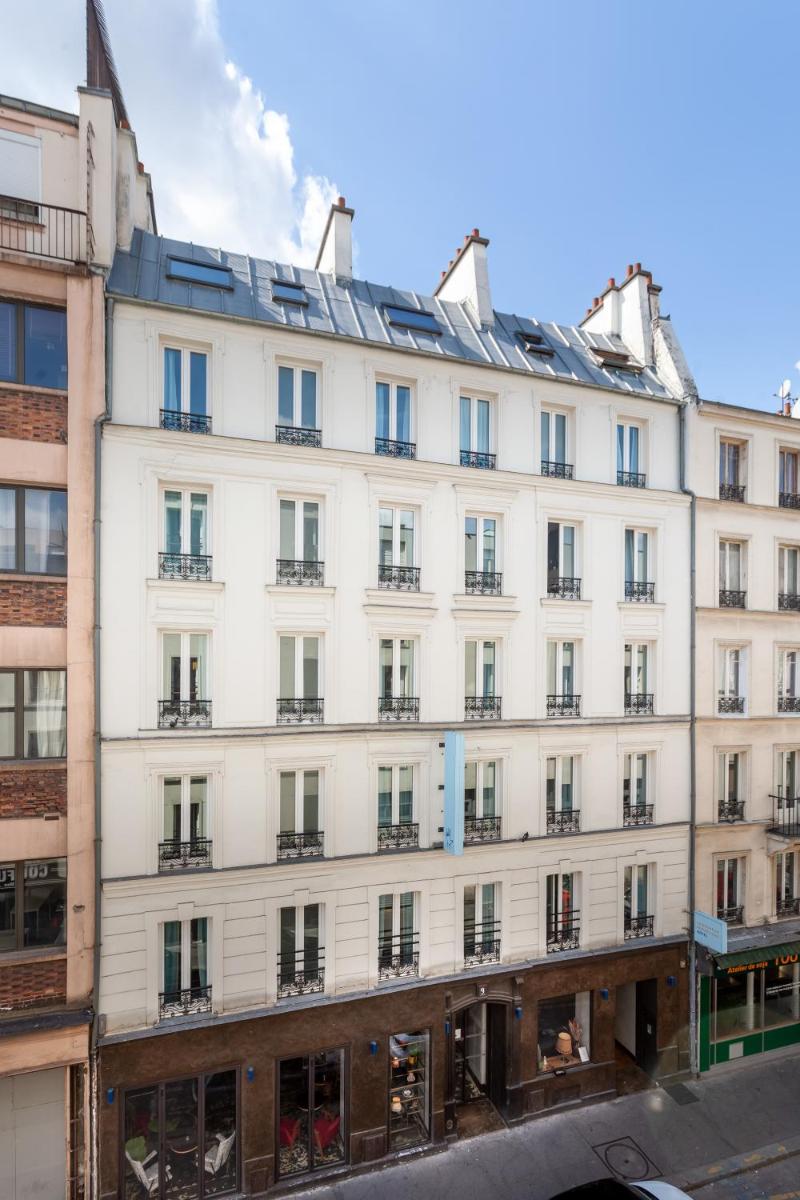 un grand bâtiment blanc avec beaucoup de fenêtres dans l'établissement Hôtel La Nouvelle République & Hammam, à Paris
