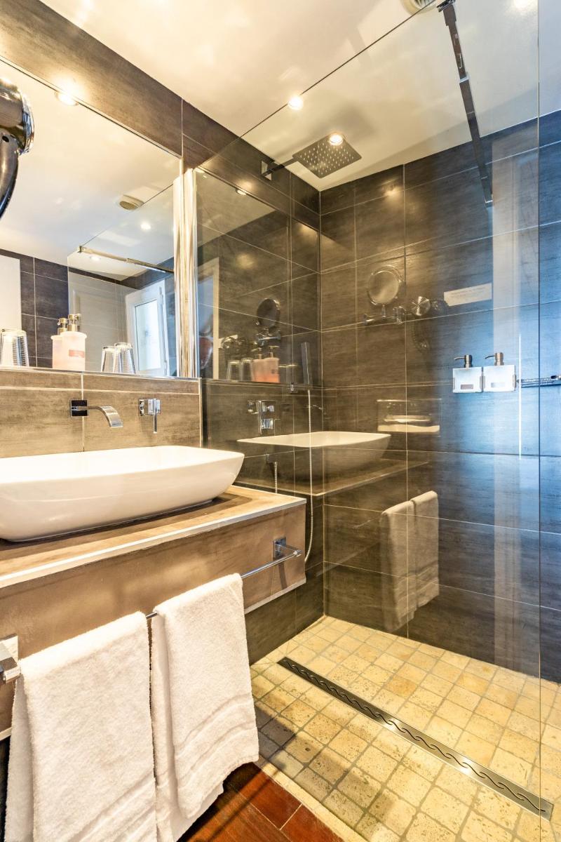 une salle de bain avec un lavabo et une douche en verre dans l'établissement Hôtel Restaurant & Spa Plaisir, au Bois-Plage-en-Ré