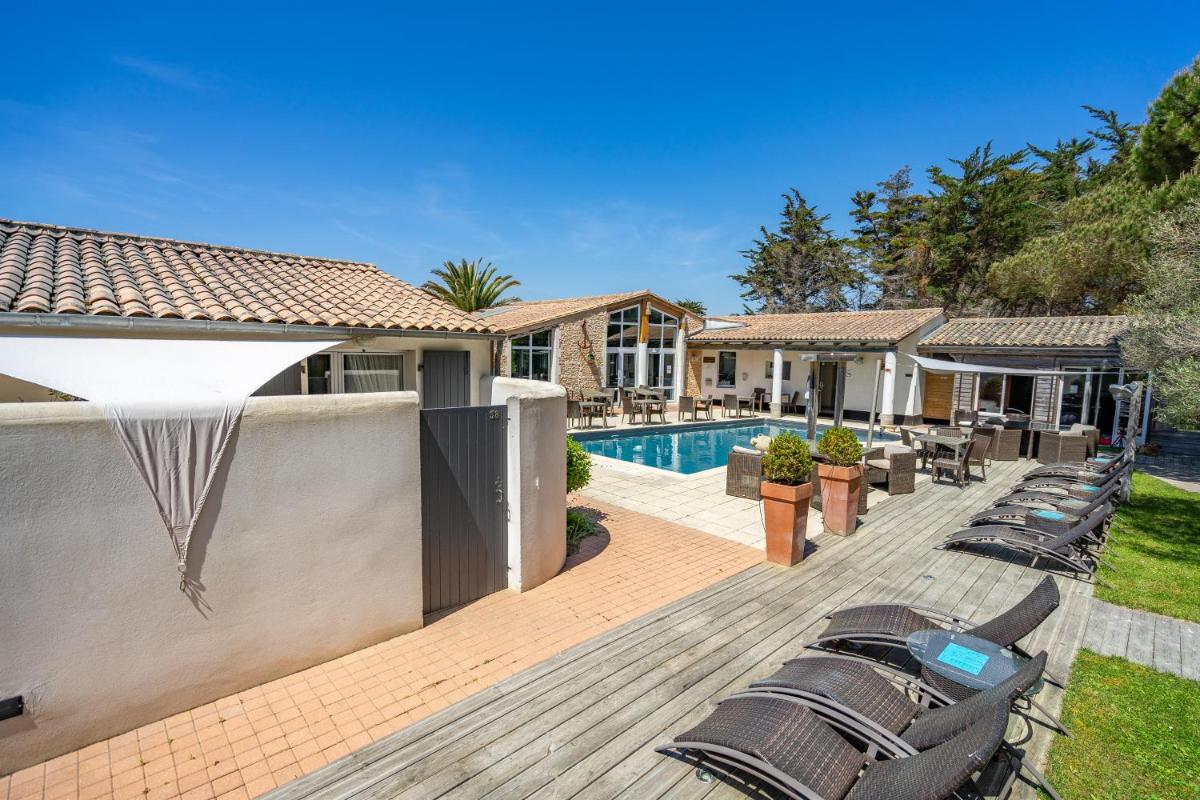 une terrasse avec des chaises et une piscine dans une maison dans l'établissement Hôtel Restaurant & Spa Plaisir, au Bois-Plage-en-Ré