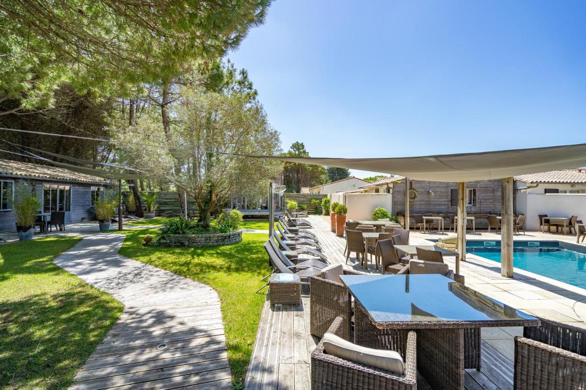 un patio avec une table et des chaises et une piscine dans l'établissement Hôtel Restaurant & Spa Plaisir, au Bois-Plage-en-Ré